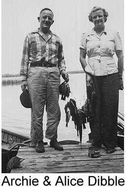 Black and white photograph of Archie and Alice Dibble standing on a dock at a lake, holding a string of fish