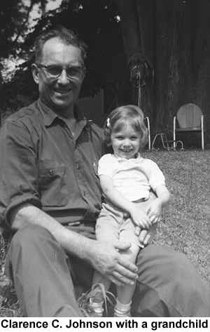 Black and white photo of Clarence C. Johnson, seated, holding a grandaughter