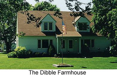 Color photo of a double frame Cape Cod house with an American flag on a flagpole in the front yard, taken 1999