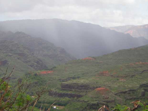 Lower Waimea Canyon: Mist-shrouded green mountains with patches of red rock here and there.