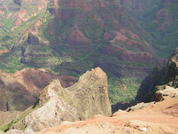 Looking down on, and beyond, a nearly razor-thin greenish gray outcropping, the red stone seems to flow downward like thick syrup under a heavy green garnish of trees and bushes. Looking down on, and beyond, a nearly razor-thin greenish gray outcropping, the red stone seems to flow downward like thick syrup under a heavy green garnish of trees and bushes.