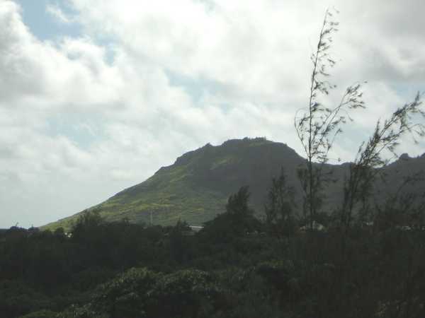 A craggy hill, dark green with vegetation, rises against a grey, cloudy sky beyond the forested rim of a deep gorge. A craggy hill, dark green with vegetation, rises against a grey, cloudy sky beyond the forested rim of a deep gorge.