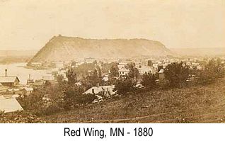 Sepia-tint wide-angle photo of the city of Red Wing, MN in 1880, showing Barn Bluff in the background