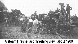 IMAGE/PHOTO: A steam thresher and threshing crew, about 1900: Black and white photo of a steam threshing machine and loader, surrounded by the men, women, and children who comprised the threshing crew and/or cooked for them, from about 1900